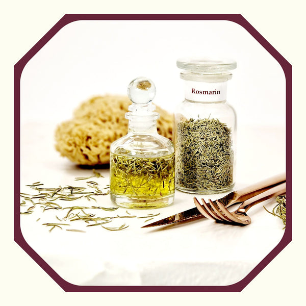 Rosmarin im Glas neben einer kleinen Flasche Rosmarin-Mandel-Öl, einem Naturschwamm, Rosmarinnadeln und Besteck