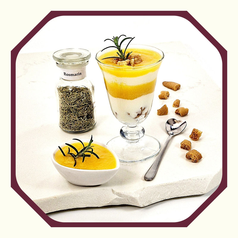 Rosmarin im Glas neben einem Dessertglas, gefüllt mit Schichten von Joghurt und Rosmarin-Pfirsichmus, eine kleine Schale Rosmarin-Pfirsichmus, ein Löffel, Keksstücke